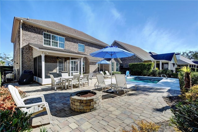 view of swimming pool featuring a sunroom, a patio, and an outdoor fire pit