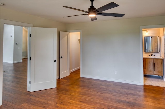 unfurnished bedroom featuring ensuite bath, ceiling fan, and dark wood-type flooring