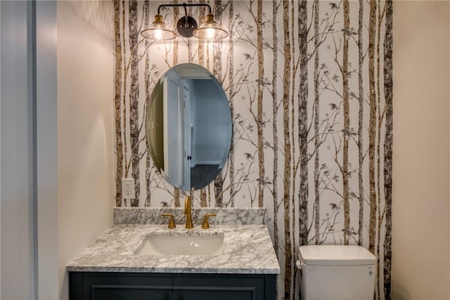 bathroom with toilet, wallpapered walls, and vanity