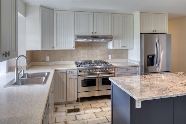 kitchen featuring decorative backsplash, appliances with stainless steel finishes, light stone counters, sink, and white cabinetry