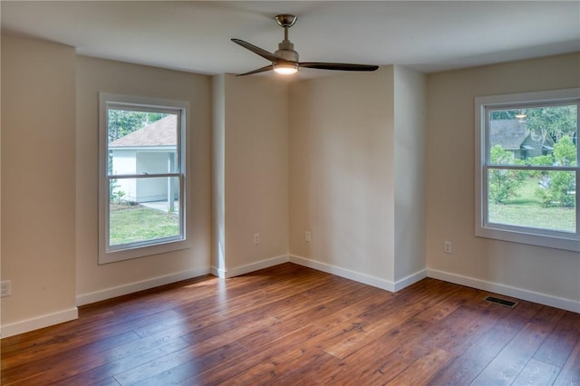 unfurnished room with ceiling fan, hardwood / wood-style flooring, visible vents, and baseboards