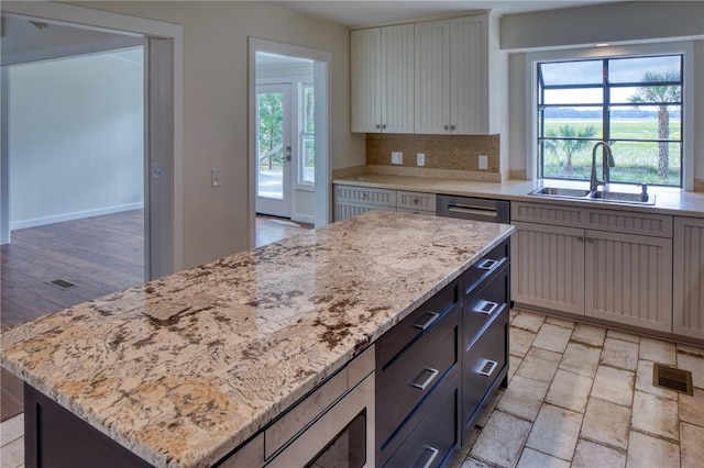 2593 Julienton Dr NE, Townsend, GA 31331 - kitchen featuring a sink, a center island, light stone counters, backsplash, and stainless steel dishwasher
