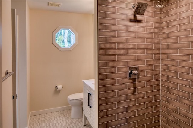 bathroom featuring visible vents, toilet, tile patterned flooring, tiled shower, and baseboards