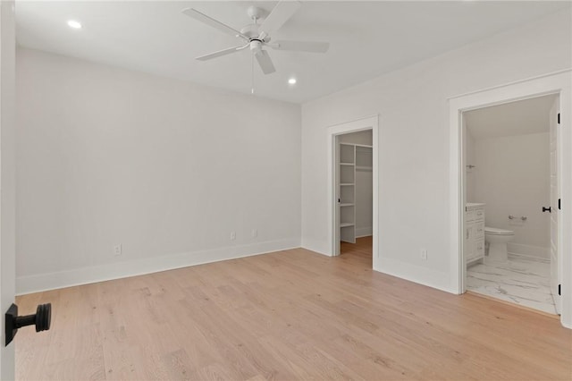 unfurnished bedroom with a walk in closet, ensuite bath, a closet, and light hardwood / wood-style flooring