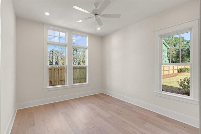 empty room featuring ceiling fan, plenty of natural light, and light hardwood / wood-style flooring