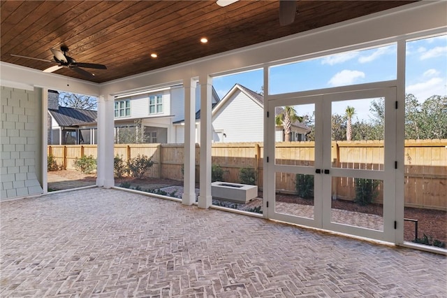 unfurnished sunroom featuring ceiling fan, plenty of natural light, and wooden ceiling