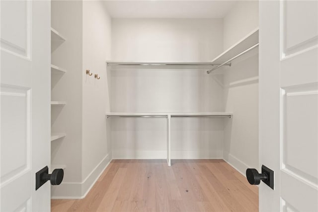 walk in closet with light hardwood / wood-style floors