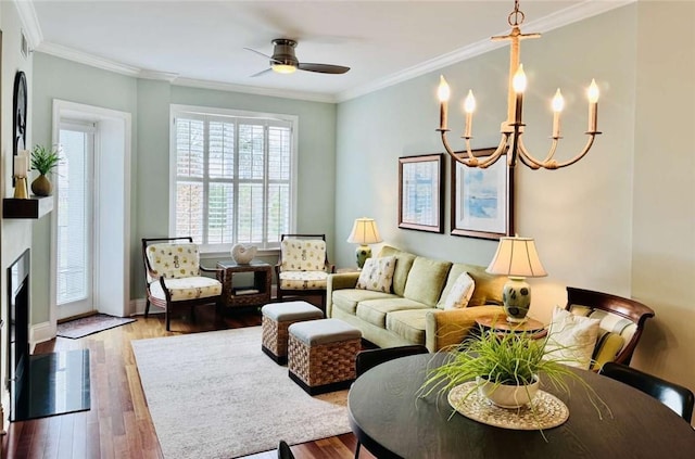 living room featuring hardwood / wood-style flooring, ceiling fan with notable chandelier, and ornamental molding