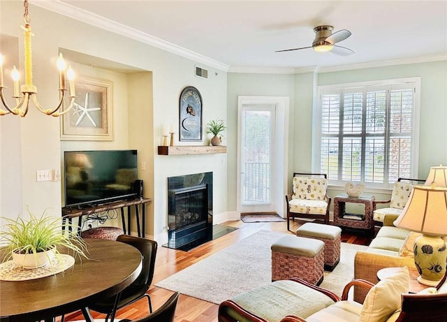 living room with ceiling fan with notable chandelier, light hardwood / wood-style floors, and ornamental molding