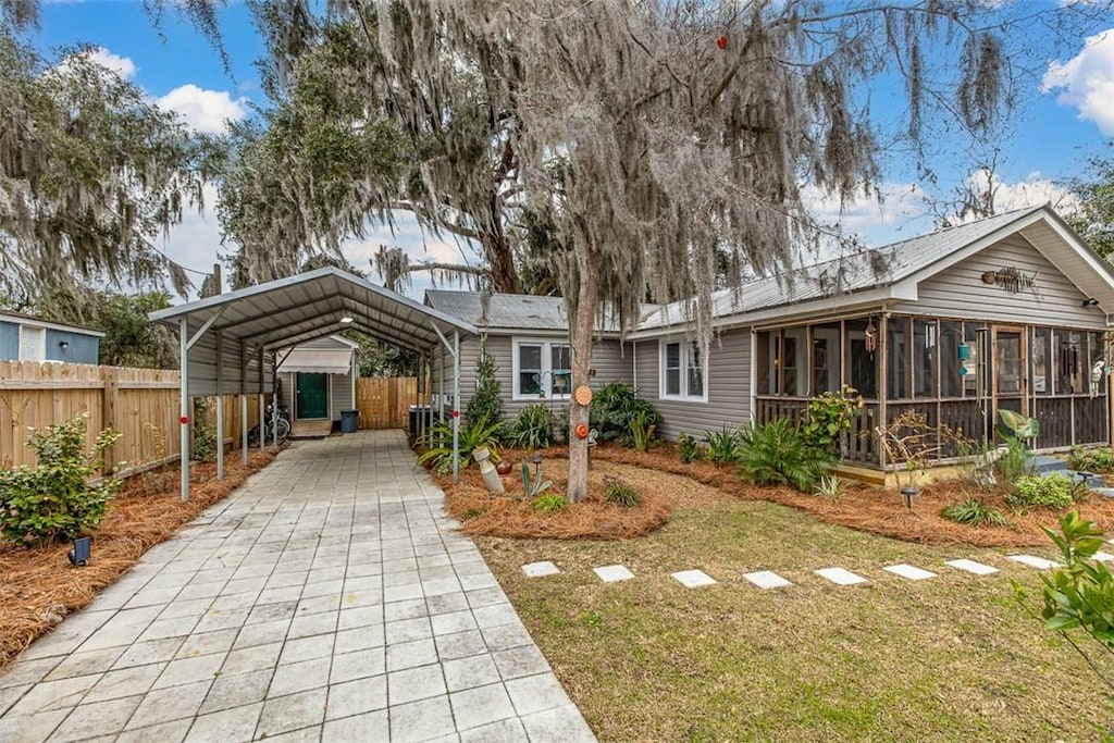 view of front facade with a carport, a front lawn, and a sunroom