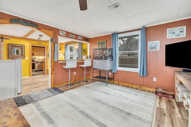 interior space featuring ceiling fan, wood-type flooring, and wooden walls