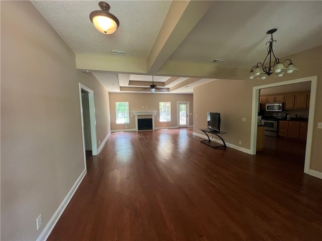 134 Hillery Trce, Brunswick, GA 31523 - unfurnished living room featuring dark wood finished floors, beamed ceiling, a fireplace, ceiling fan, and a chandelier