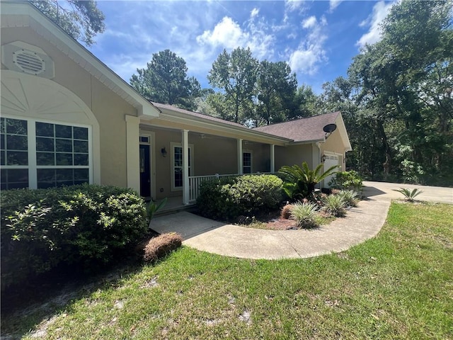 134 Hillery Trce, Brunswick, GA 31523 - view of side of property featuring stucco siding, a garage, a porch, and a yard
