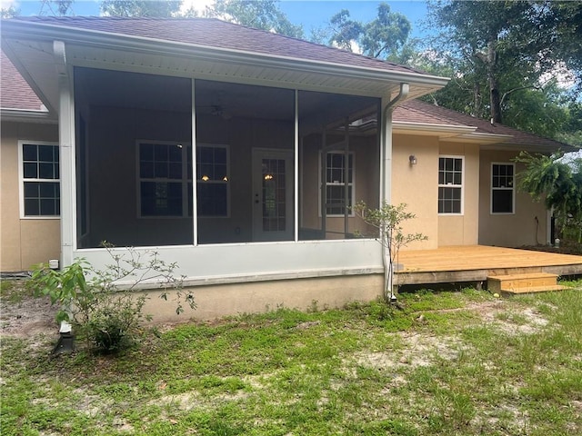 134 Hillery Trce, Brunswick, GA 31523 - back of property featuring a sunroom, stucco siding, a shingled roof, and a wooden deck