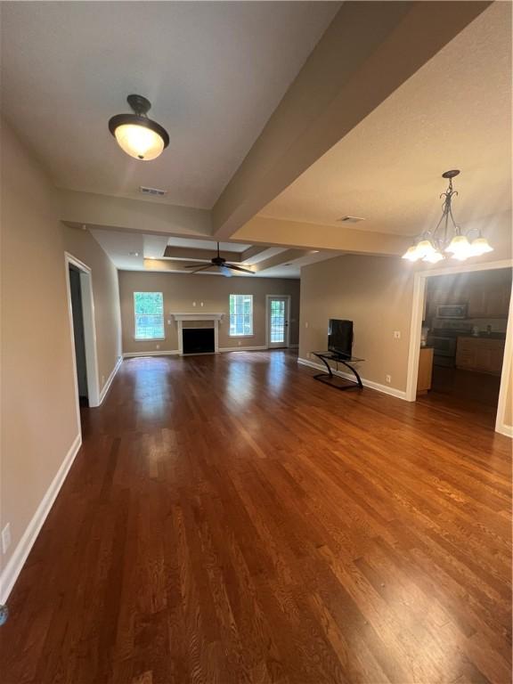 134 Hillery Trce, Brunswick, GA 31523 - unfurnished living room with wood finished floors, beam ceiling, a chandelier, and a fireplace