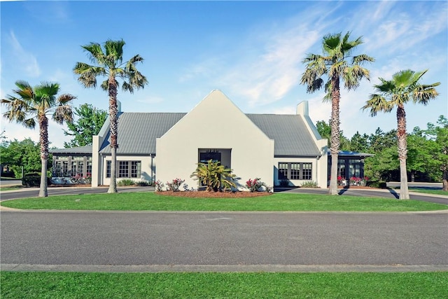 222 Bottlebrush Walk, Brunswick, GA 31525 - view of front of house featuring a metal roof, a chimney, and stucco siding