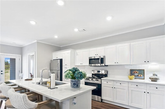 222 Bottlebrush Walk, Brunswick, GA 31525 - kitchen with stainless steel appliances, ornamental molding, white cabinets, a center island with sink, and a kitchen breakfast bar