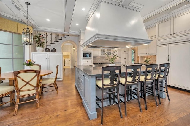 117 Hawkins Island Cir, Saint Simons Island, GA 31522 - kitchen featuring built in appliances, custom range hood, light wood finished floors, decorative backsplash, and crown molding