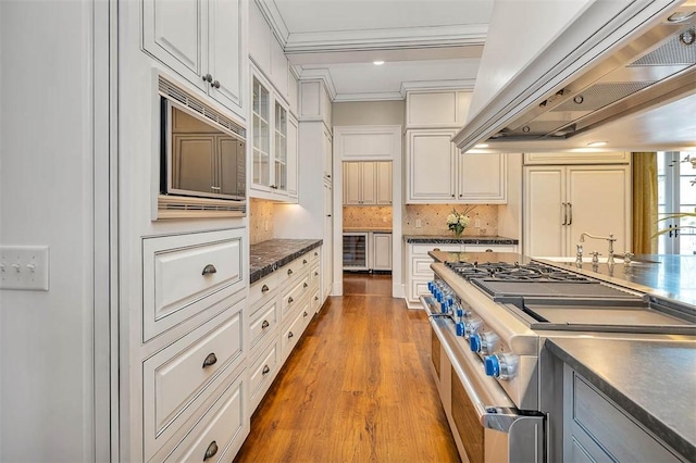 117 Hawkins Island Cir, Saint Simons Island, GA 31522 - kitchen with custom exhaust hood, stainless steel appliances, beverage cooler, crown molding, and dark countertops