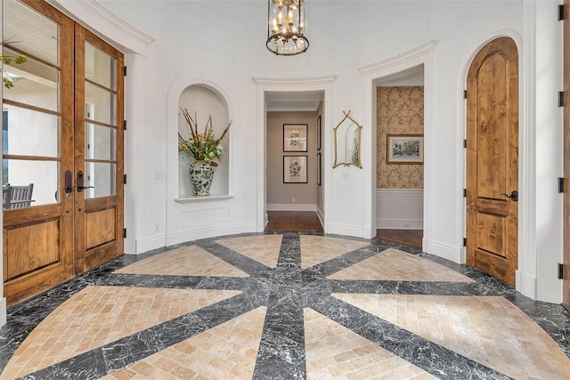 117 Hawkins Island Cir, Saint Simons Island, GA 31522 - foyer entrance with inlaid floor details, a chandelier, arched walkways, french doors, and baseboards