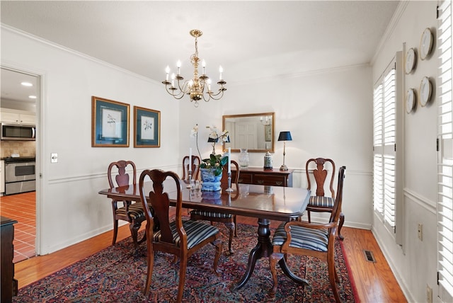 dining area featuring an inviting chandelier, wood-type flooring, and ornamental molding