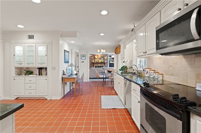 kitchen with sink, white cabinetry, hanging light fixtures, stainless steel appliances, and tasteful backsplash