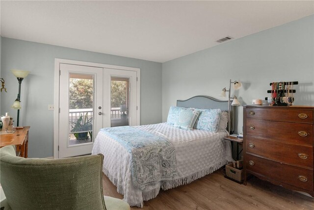 bedroom featuring access to outside, wood finished floors, visible vents, and french doors