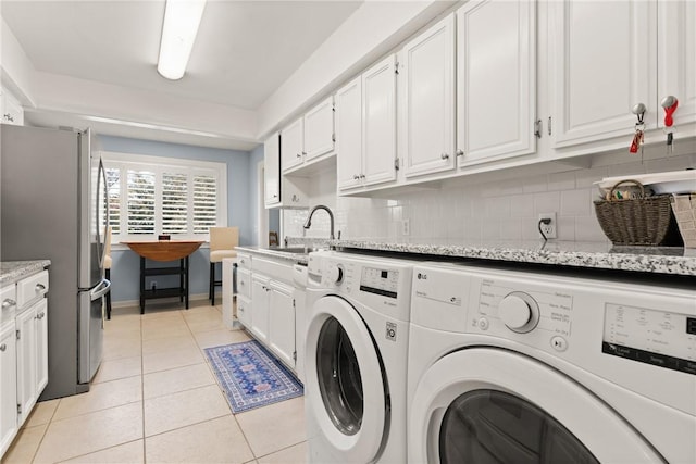 laundry area featuring washer and dryer, light tile patterned floors, baseboards, and a sink