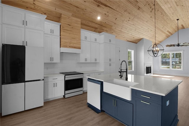 kitchen with electric range, a sink, blue cabinetry, freestanding refrigerator, and white dishwasher