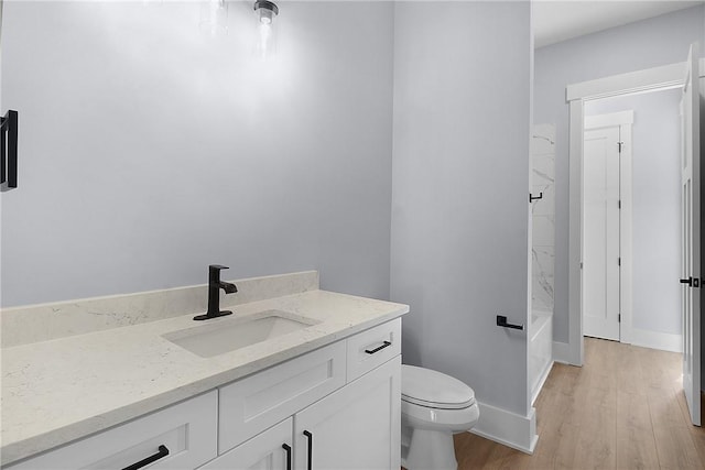 bathroom with toilet, vanity, baseboards, and wood finished floors