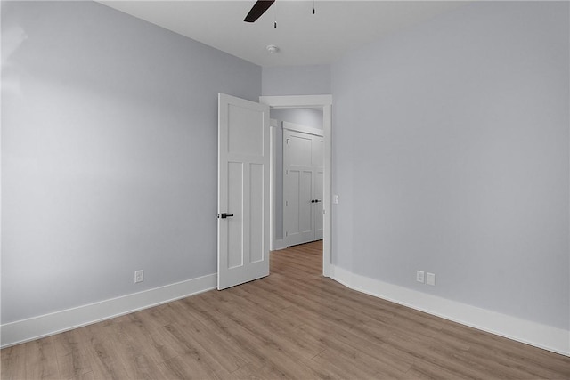 spare room with a ceiling fan, light wood-style floors, and baseboards