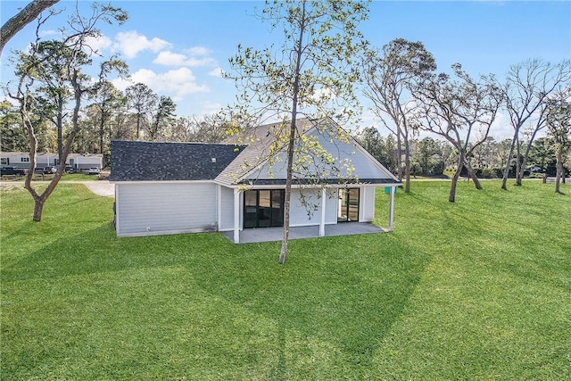 back of house featuring a patio area, a lawn, and a shingled roof