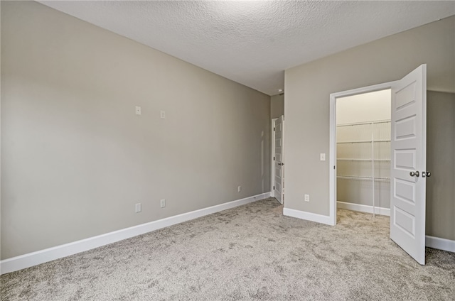 154 Ossabaw Way, Waverly, GA 31565 - unfurnished bedroom with carpet flooring, baseboards, a spacious closet, a textured ceiling, and a closet