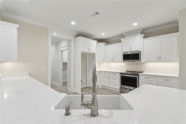 154 Ossabaw Way, Waverly, GA 31565 - kitchen with stainless steel appliances, ornamental molding, recessed lighting, white cabinets, and light wood-style flooring