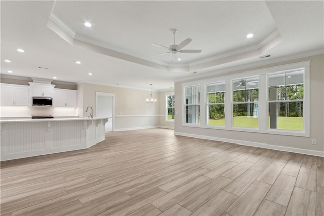 154 Ossabaw Way, Waverly, GA 31565 - unfurnished living room with a ceiling fan, a raised ceiling, crown molding, a chandelier, and light wood-type flooring