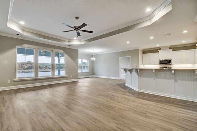 154 Ossabaw Way, Waverly, GA 31565 - unfurnished living room with crown molding, a tray ceiling, a ceiling fan, light wood-style floors, and baseboards