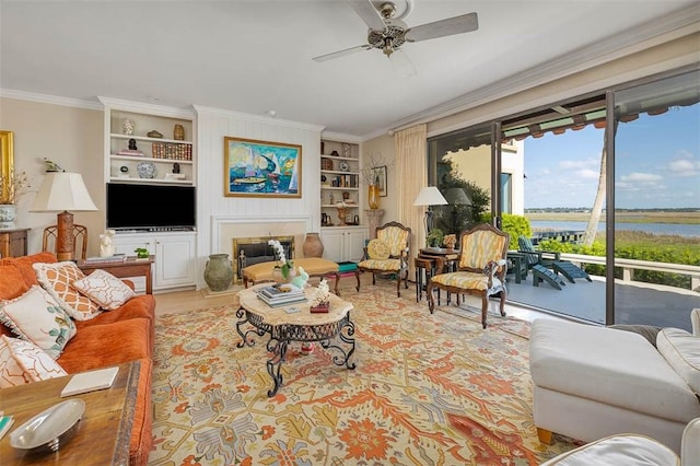 1212 River Club Dr, Sea Island, GA 31561 - living area with built in shelves, a ceiling fan, ornamental molding, a water view, and a glass covered fireplace