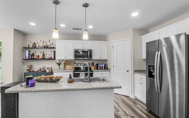 352 Pecan Pointe Dr, Brunswick, GA 31525 - kitchen with appliances with stainless steel finishes, light wood-type flooring, white cabinetry, a kitchen island with sink, and recessed lighting
