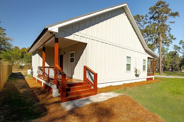 rear view of house with board and batten siding, a porch, and a yard