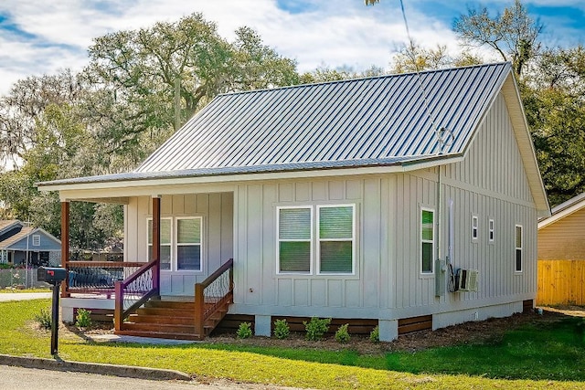 view of front facade featuring metal roof, fence, board and batten siding, and a porch