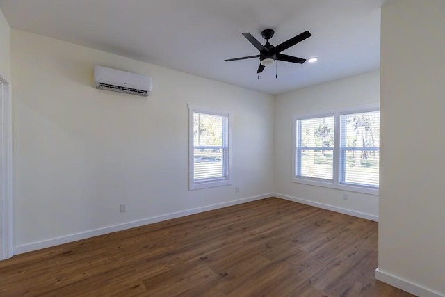 empty room with dark wood-type flooring, a wall mounted air conditioner, ceiling fan, and baseboards