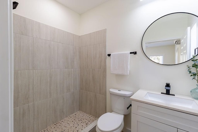 full bathroom featuring toilet, tiled shower, and vanity