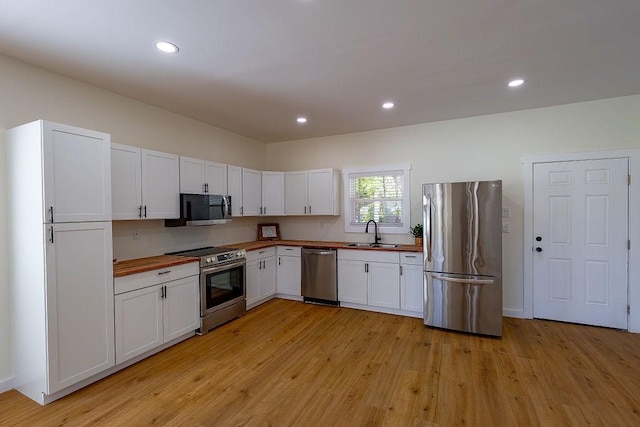 kitchen with light wood-style floors, a sink, stainless steel appliances, and butcher block counters