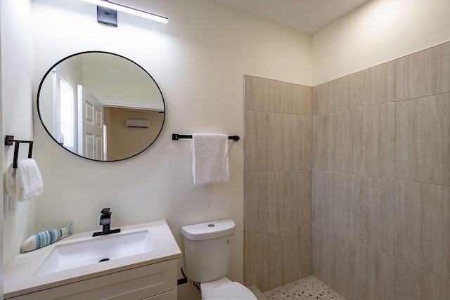 bathroom featuring toilet, vanity, and a tile shower