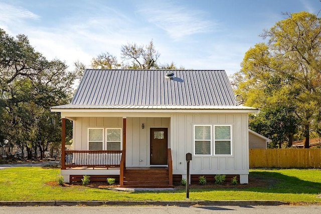 view of front facade with fence, board and batten siding, a porch, and a front yard