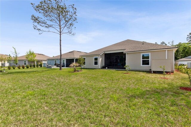 316 Chinquapin Dr, Saint Marys, GA 31558 - back of property with a yard, a sunroom, roof with shingles, and stucco siding