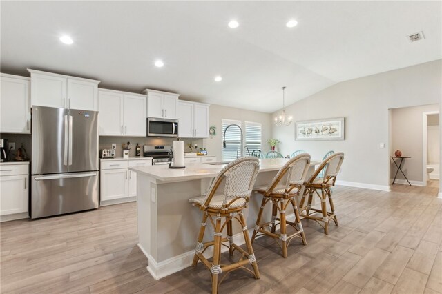 316 Chinquapin Dr, Saint Marys, GA 31558 - kitchen with stainless steel appliances, vaulted ceiling, light wood-style floors, a kitchen breakfast bar, and a kitchen island with sink