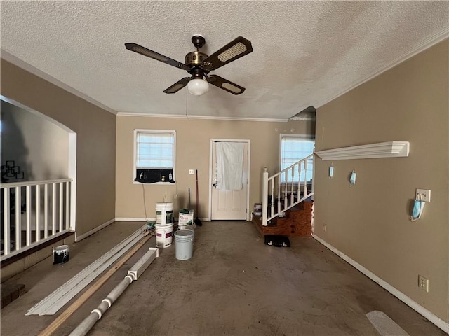 living room featuring ceiling fan, a textured ceiling, and ornamental molding