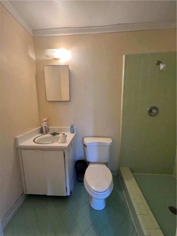 bathroom with vanity, tile patterned flooring, toilet, ornamental molding, and tiled shower