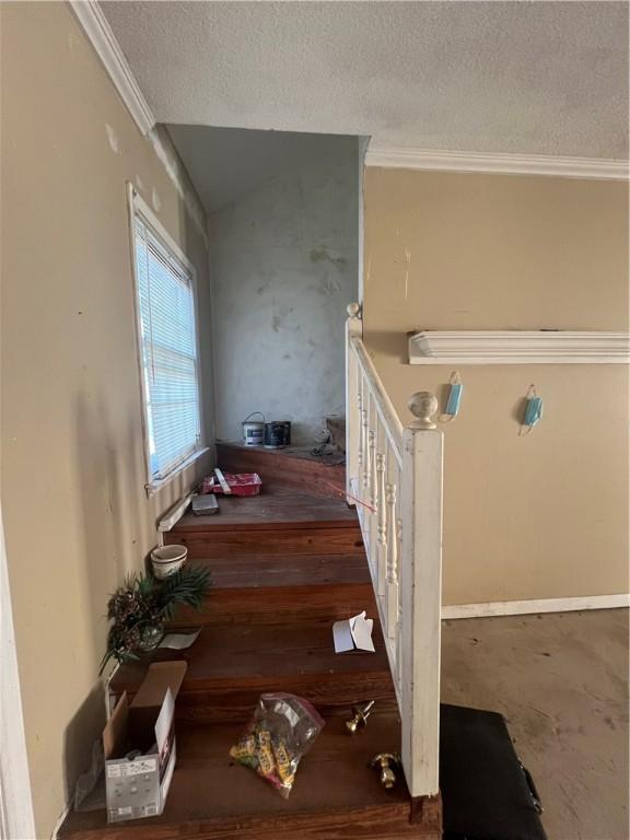 stairway featuring a textured ceiling and ornamental molding